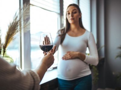 Pregnant woman declining glass of red wine. Adobe